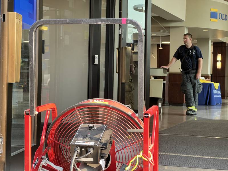 DeKalb firefighter Jared Thorpe stands inside 310 W. State St. in. Sycamore as a fan vents fresh air into the Old National Bank building after an elevator motor caused smoke to fill an elevator shaft in the building around 6 p.m. on Wednesday June 21, 2023.