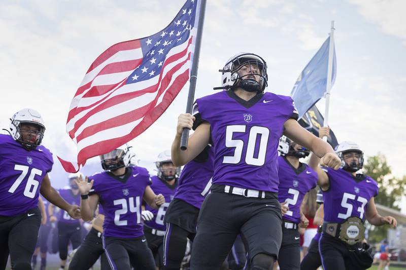 Dixon’s Aidan Hogard carries the American flag Friday, Aug. 30, 2024, as the Dukes take the field against Stillman Valley to start the 2024 football season.