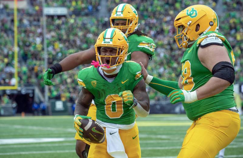 Oregon running back Bucky Irving celebrates after his touchdown against Washington State with offensive lineman Jackson Powers-Johnson, right, and offensive lineman Steven Jones, back, during the first half of a 2023 game in Eugene, Ore.