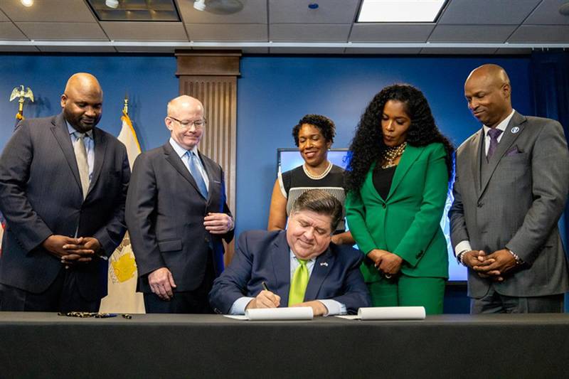Flanked by the lieutenant governor and legislative leaders, Gov. JB Pritzker signs the $53.1 billion fiscal year 2025 state budget into law after months of negotiations.