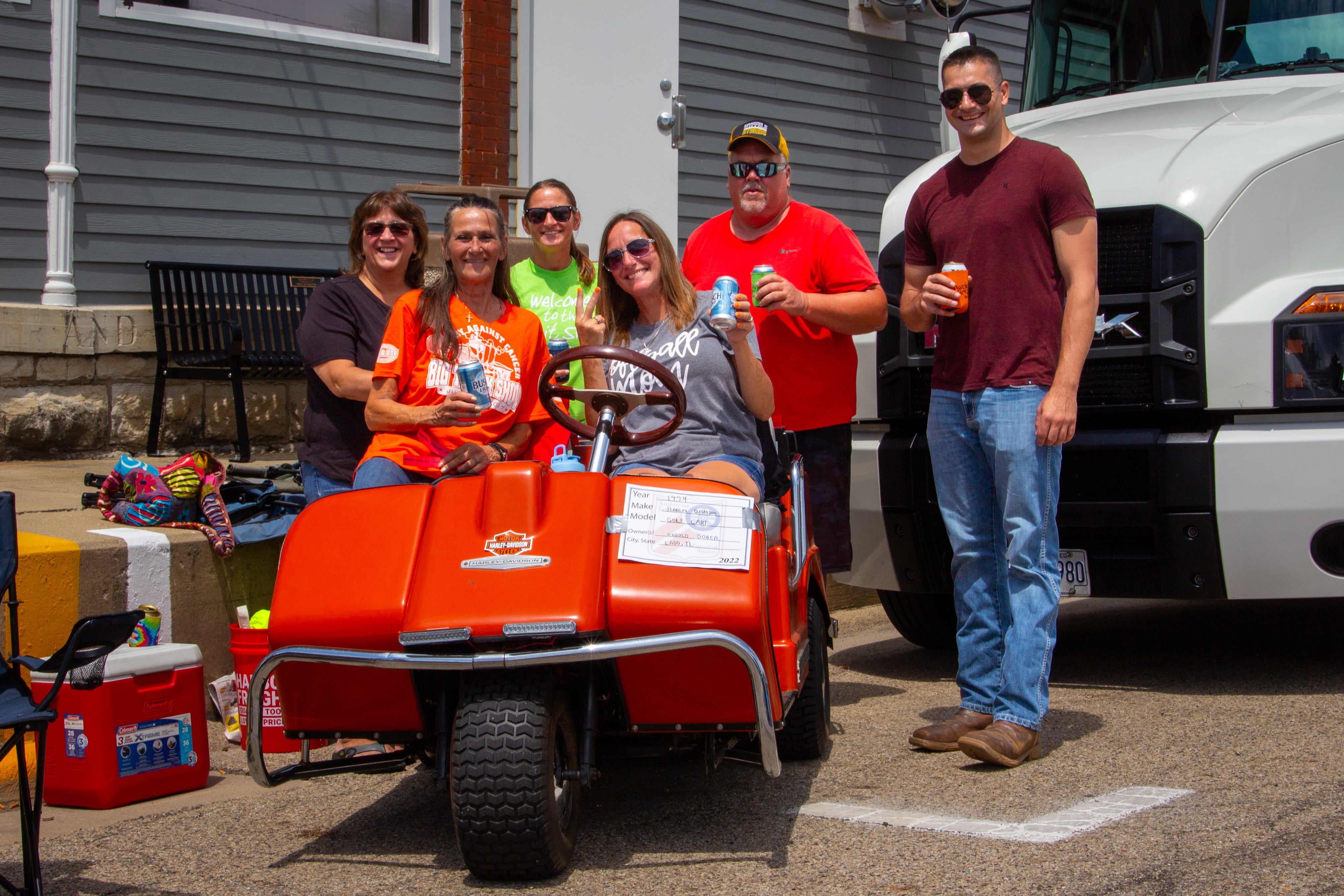 Family of the late Harold Dober pose for picture in front of his golf cart on Saturday, July 20, 2024 at the Convoy Against Cancer Big Truck Show on Main Avenue in Ladd.