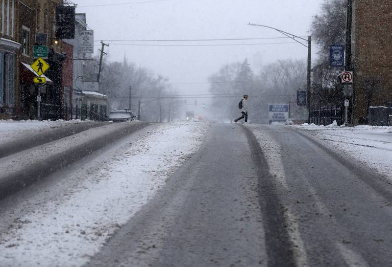 A pedestrian crosses Illinois 31 in Richmond as a winter storm moves through McHenry County on Tuesday, Jan. 9, 2024, delivering snow to most of the county.