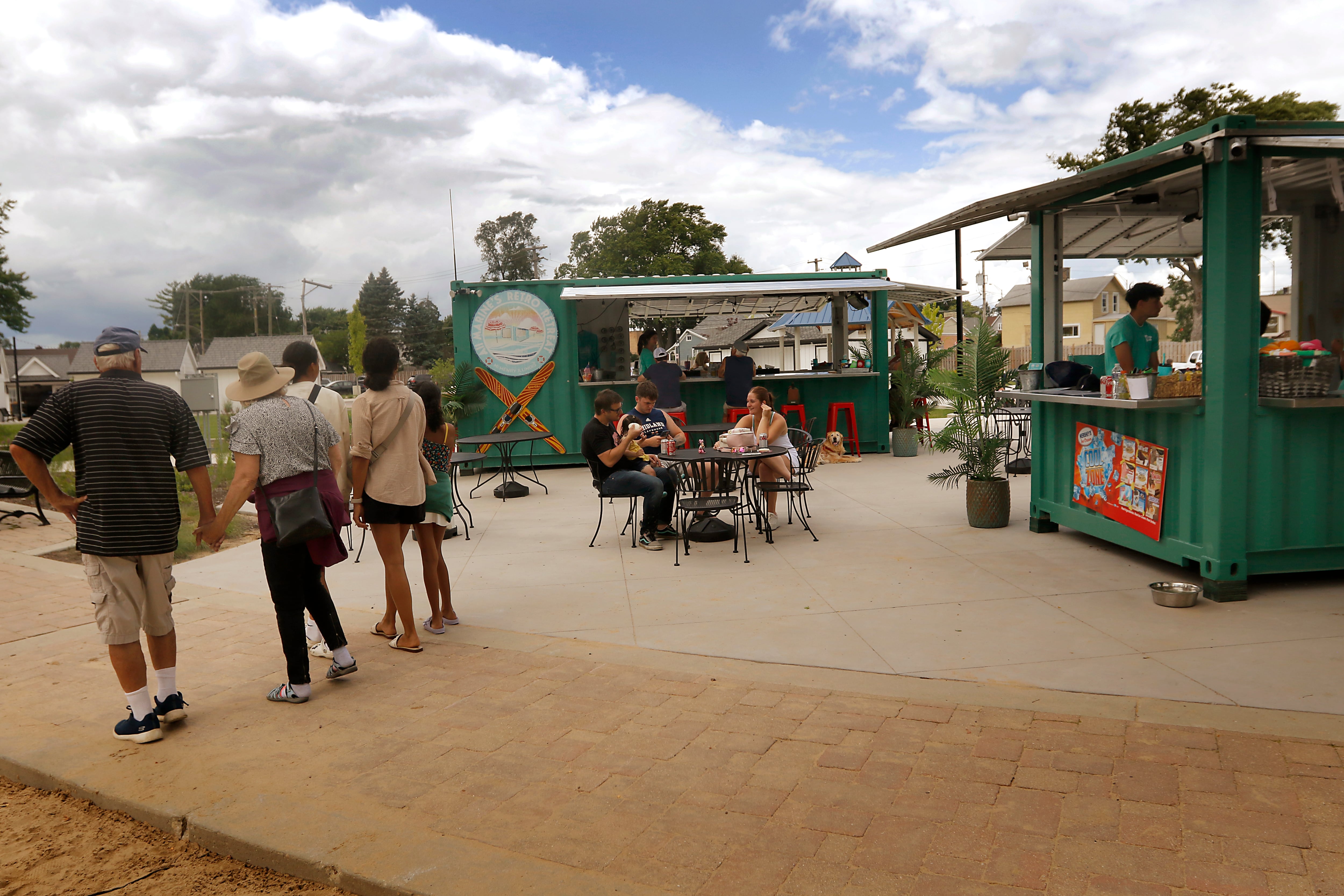 People walk past All Marine’s Retro Rentals and the Retro Retreat Beach Bar in McHenry’s Miller Point Park.