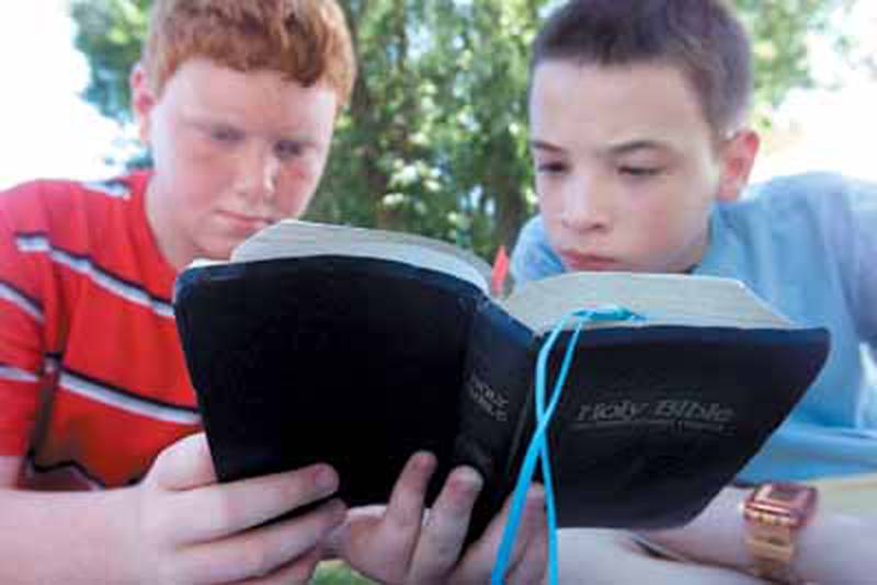 Micah Fagerstrom, 11, and Derek Neff, 13, listen to a Bible passage Friday at the First Baptist Church Day Camp. About 75 children ranging in ages from 6 to 13 participated each day in various activities during the weeklong camp.