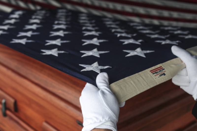 An American flag is pulled over the empty casket of World War II veteran Arthur Countryman on Friday, Aug. 6, 2021, at Plainfield Township Cemetery in Plainfield, Ill.