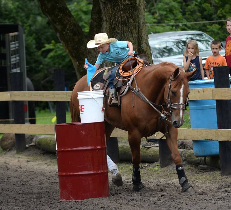 Braxton Chapman, 6, of Earlville, plants a flag in a barrel as his horse patiently waits during the Flags Competition at the Rock River Trail & Horseman Association's Grand Opening Show on Saturday, July 20, 2024.