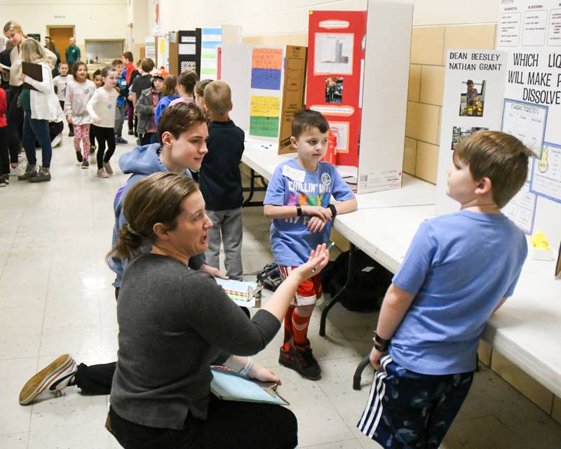 Science Fair Judge Karsen Kras a student at Downers North, left, and Ginny Keeling a scientist in the Downers Grove area judge Nathan Grant, center, and Dean Beesley science project during the School District 58 Science Fair held at O’Neill Middle School in Downers Grove on Saturday Jan. 20, 2024.