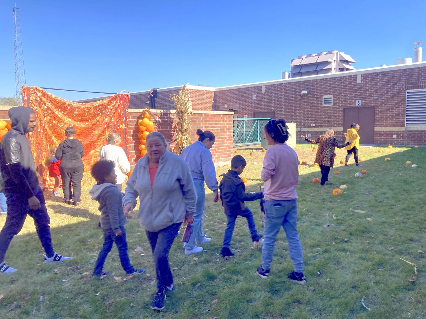 Jacey Desmarais and parents of her students help students pick pumpkins at the pumpkin farm set up at Sator Sanchez Elementary School in Joliet on Friday. Oct. 18, 2024.