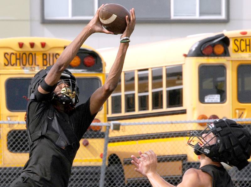 Sandwich football player Simeion Harris picks off a pass during a passing drill on the first day of football practice at Sandwich High School on Monday, Aug. 12, 2024.