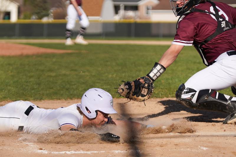 Plano's Nick Serio (11) slides into home beating the throw to the plate for a run during a baseball game against Marengo at Plano High School on Monday, April 8, 2024.