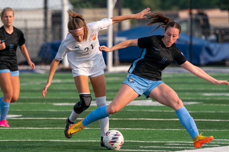 St. Charles North's Rian Spaulding (5) challenges Wheaton Warrenville South's Ashlyn Adams (21) for the ball during the Class 3A girls soccer regional final at St. Charles North High School on Friday, May 19, 2023.