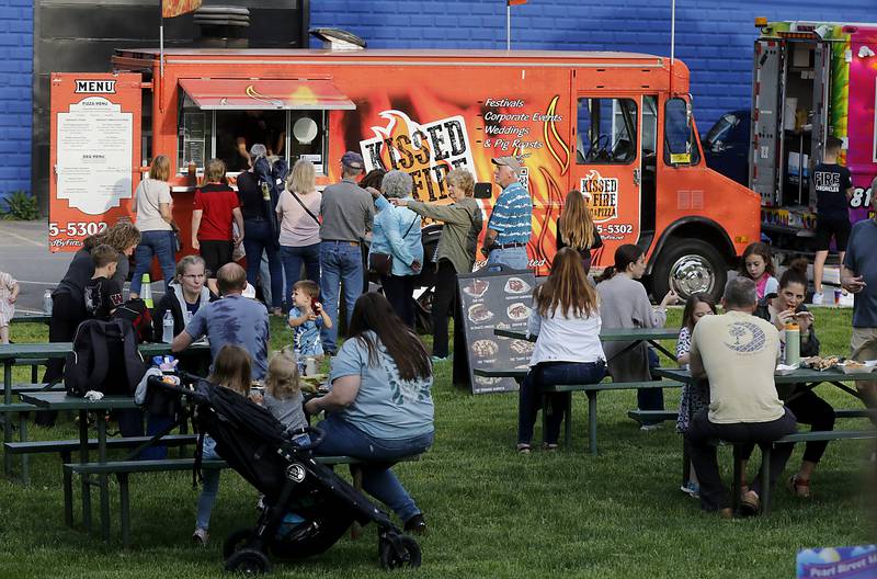 People dine and wait for food from one of the food trucks on Thursday, May 16, 2024, during McHenry's Pearl Street Market and concert at Veteran's Memorial Park. The market features around 35 venders and live music on Thursdays through Sept. 19.