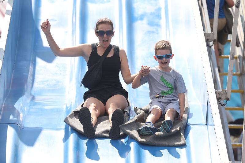 Jennifer Hylas, of plainfield rides down the slide with her son Xander Lowe, 8-years-old, at Plainfield Fest on Saturday June 29, 2024.