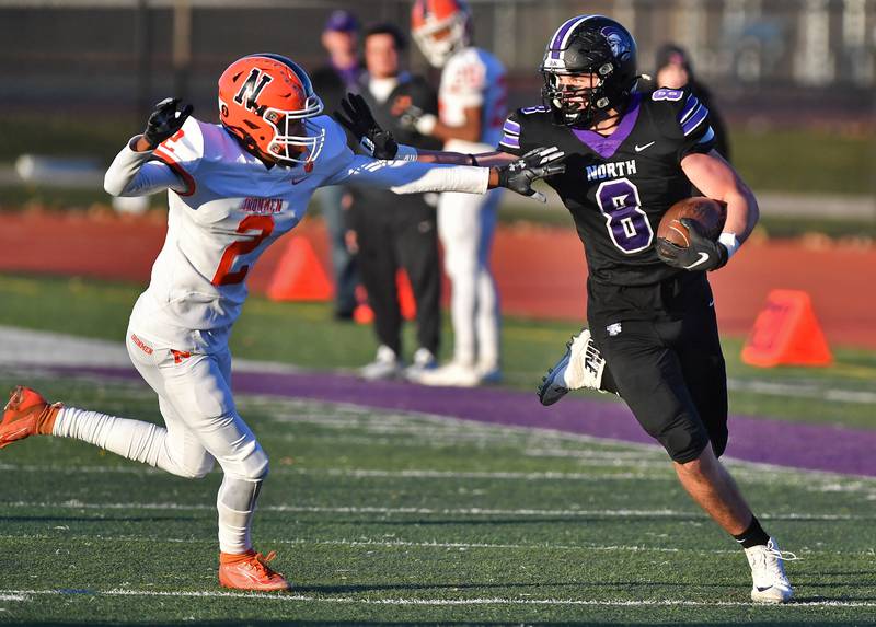 Downers Grove North's Joe Edwards (8) straight arms Normal Community's Anton Cassell after a pass reception during an IHSA Class 7A semifinal game on Nov. 18, 2023 at Downers Grove North High School in Downers Grove .