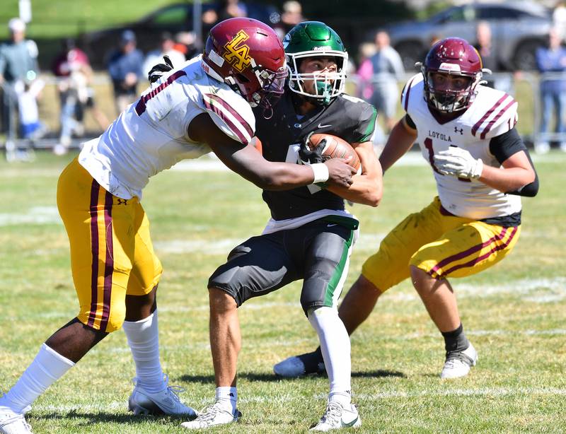 Glenbard West's Mason Ellens (middle) tries to break the tackle of Loyola's Donovan Robinson (1) during a game on September 7, 2024 at Glenbard West High School in Glen Ellyn.