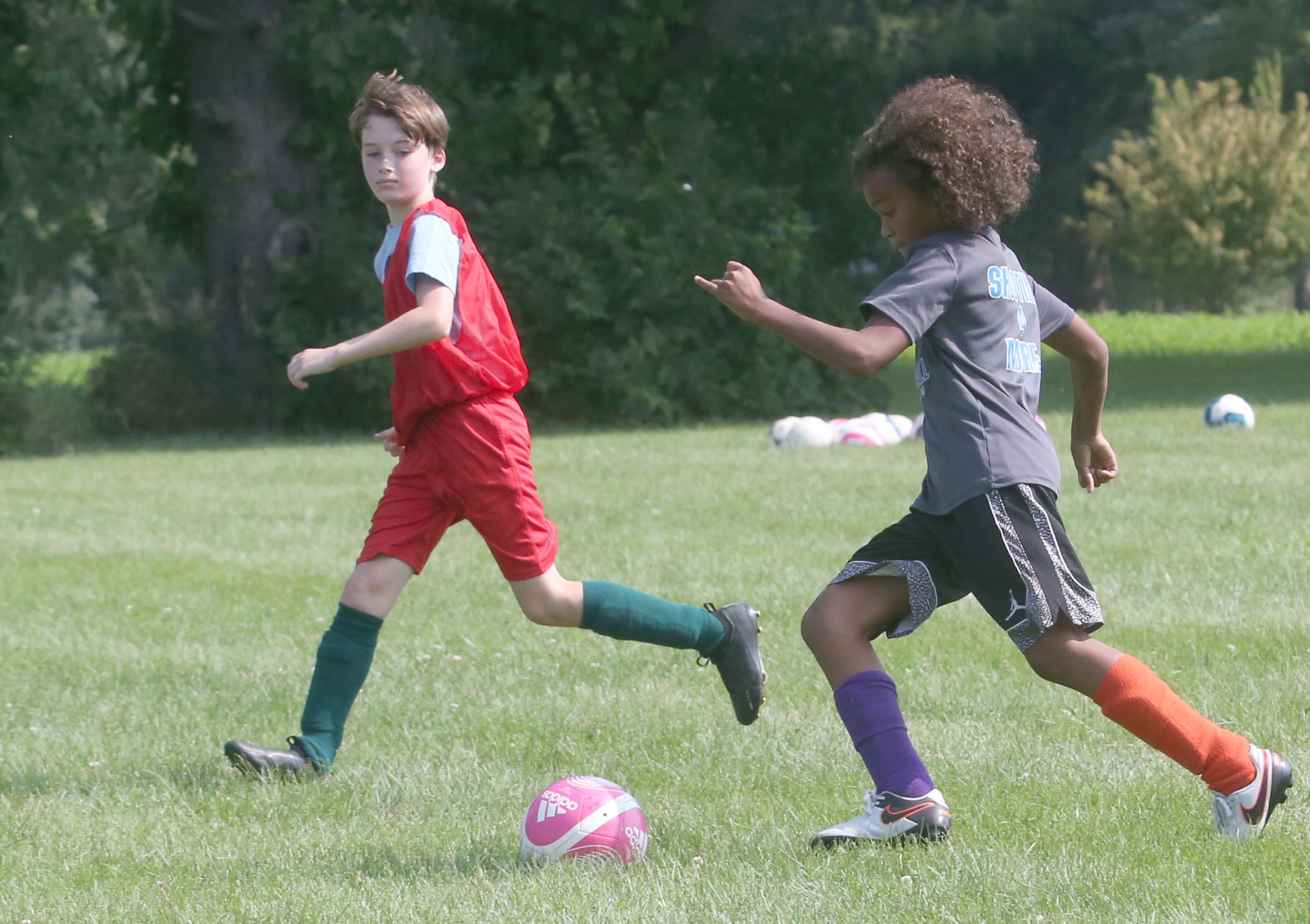 Apollo Mencos kicks the ball up the field as Pete Bonucci runs along side during the Astra Soccer Program on July 25, 2024 at Jefferson School in Princeton. The free clinic is held two days a week and is open to boys and girls from birth years 2007-2018. For more information visit www.astrasoccer.com