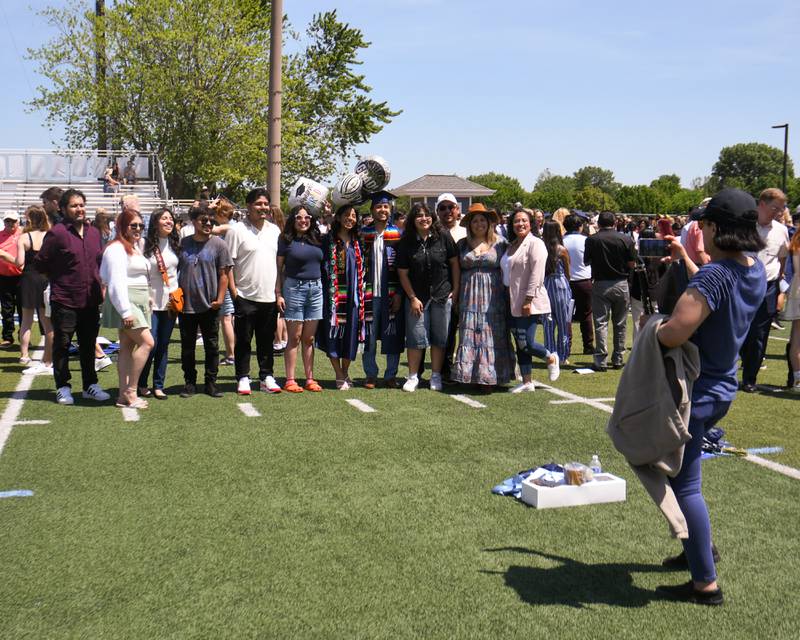 Graduates of Downers Grove South Abril Nieto Sierra and friend Kevin Garduno along with their families pose for a photo after the graduation ceremony on Sunday May 19, 2024, held at Downers Grove South High School.