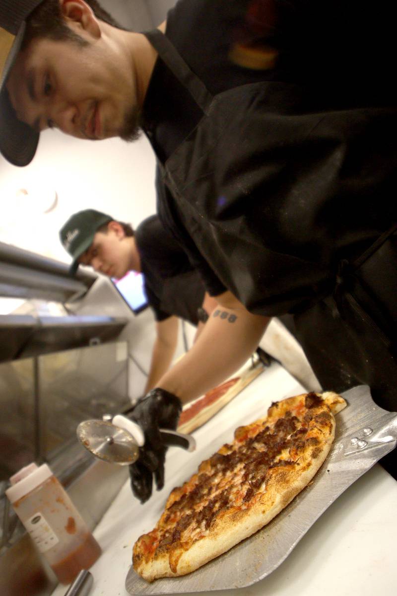 Cook Alex Farias prepares a Chicago-style cheesy beef pizza at Pickle Haus Friday night. Darryl Postelnick, known in social media circles of “Cooking With Darryl” fame, collaborated with Pickle Haus to create the special menu item.