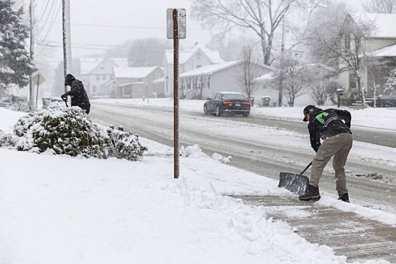 Prestige Lawn and Snow Removal’s Andres Bonilla (left) and Daniel Cadenas clear a walkway in Sterling Tuesday, Jan. 9, 2024.