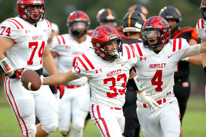 Huntley’s Charles Condon III, center, celebrates after hauling in an interception as teammate Dylan Pease, right, congratulates him in varsity football on Friday, Aug. 30, 2024, at Metcalf Field on the campus of Crystal Lake Central High School in Crystal Lake.