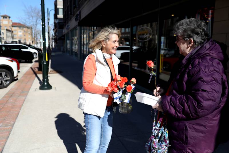 Random Acts Matter volunteer Sharon LeGare (left) hands an orange rose to Emily Prevost in St. Charles as part of Random Acts of Kindness Week on Wednesday, Feb. 14, 2024.
