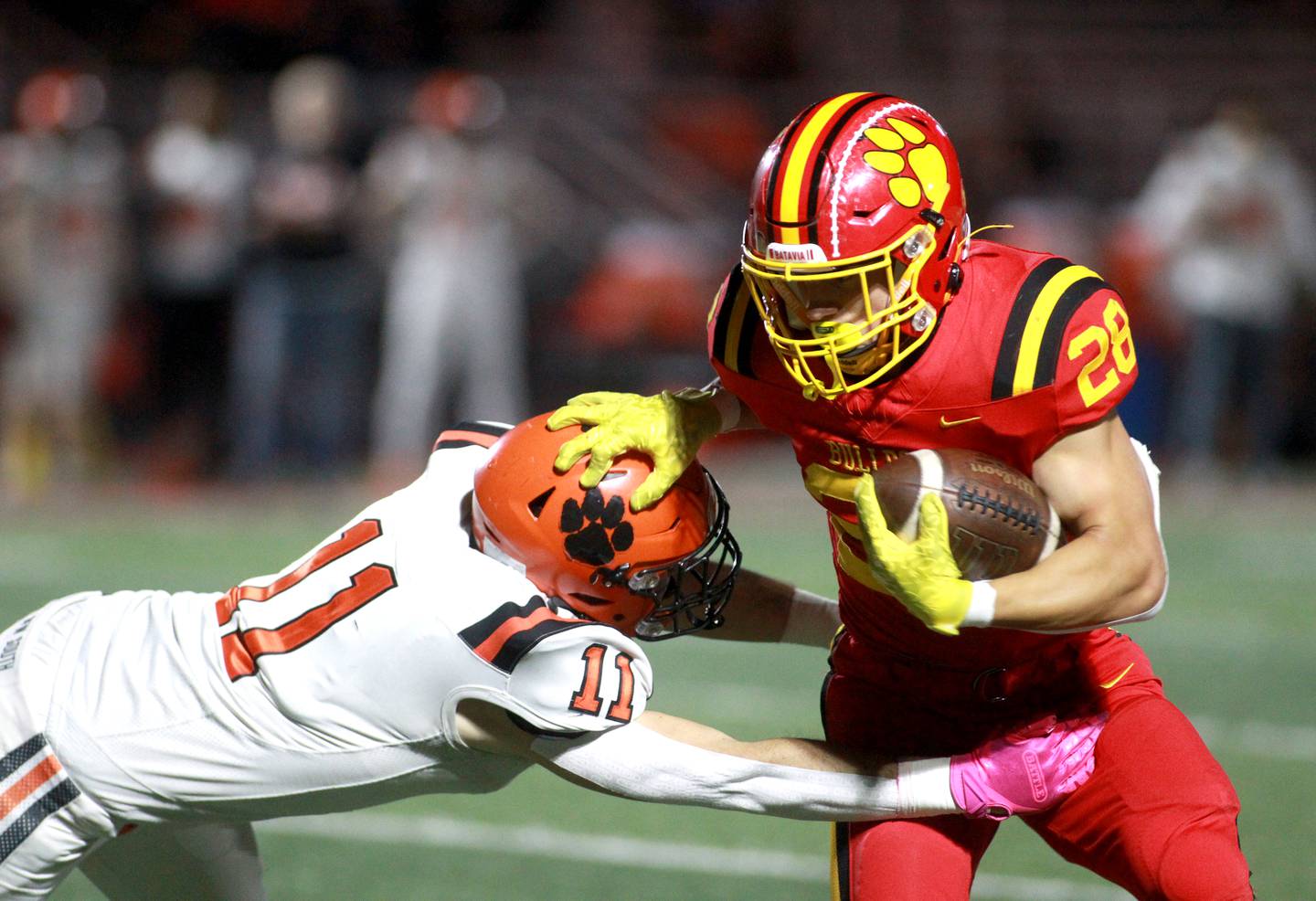 Batavia’s Nathan Whitwell holds off a tackle by Wheaton Warrenville South’s Zach Rogers on Friday, Oct. 18, 2024 during a game at Batavia.