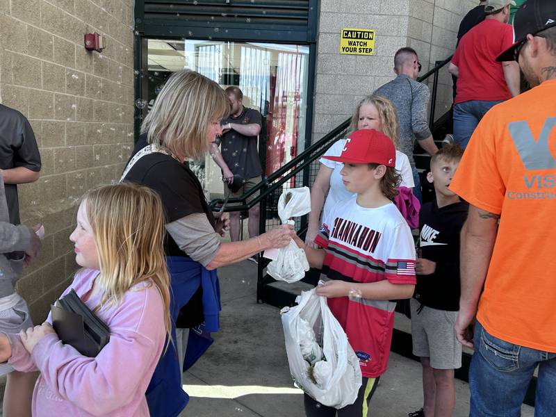 Channahon Mustangs little league players pass out saplings to Joliet Slammers fans at Duly Health and Care Field on May 11, 2024.