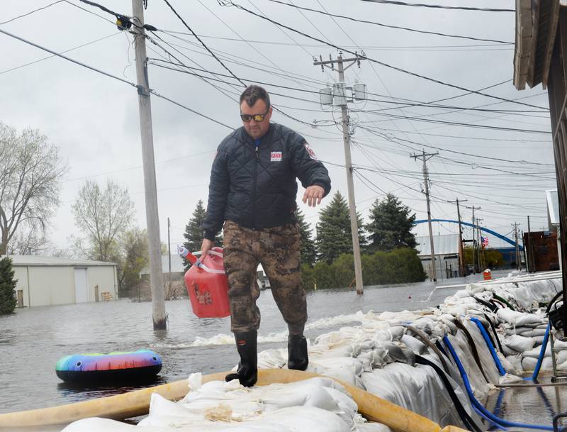 Jacob Helms, a volunteer firefighter with the Savanna Fire Department, walks on top of the sandbag wall as he refuels pumps just west of Main Street in the city's downtown Sunday. Firefighters along with volunteers and inmates from Kewanee and East Moline, constructed the wall with 46,000 sand bags in anticipation of river levels rising past the 21-foot mark.