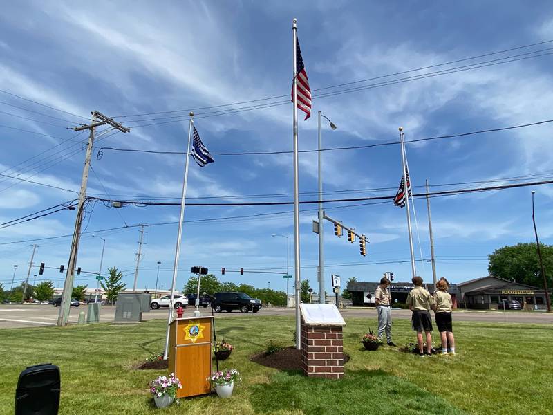 Scouts from DeKalb Scout Troop 33 hoist police and fire flags at the new first responders memorial outside Isaac Executive Suites, 2675 Sycamore Road, DeKalb, during a dedication ceremony held Sunday, May 19, 2024. The memorial was unveiled at the close of National Police Week.