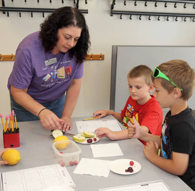 Youth Services Manager Gina Knowlton helps Luke Krall and Landon Soderstrom with an experiment at the Town and Country Library on Friday, June 21, 2024 in Elburn.