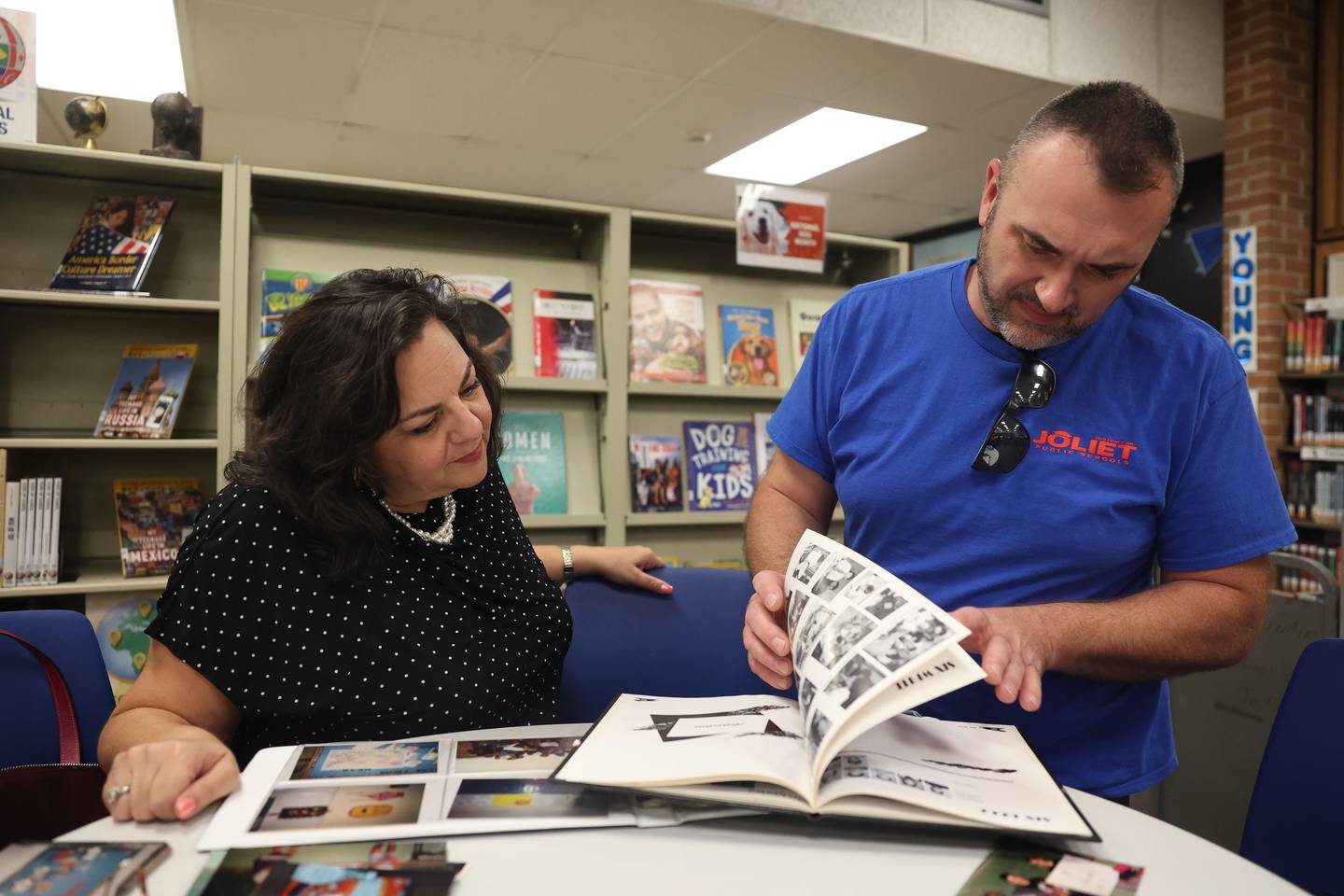 Evan Giardina looks over a 1992-93 Hufford yearbook he helped put together when he was in seventh grade in Judith Nash’s Yearbook Club at Hufford Junior High School on Friday, August 23, 2024 in Joliet. Now, 31 years later, Giardina and Nash both work for District 86.