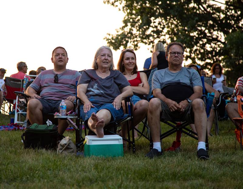 Attendees sit and watch band Hello Weekend perform during North Aurora's annual Independence Day celebration at Riverfront Park  in North Aurora on Monday, July 3, 2023.