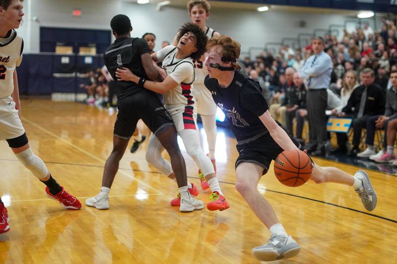 Oswego East's Andrew Pohlman (21) drives the baseline off of a pick by Andrew Wiggins (1) against Benet’s Jayden Wright (3) during a Class 4A Oswego East regional final basketball game at Oswego East High School on Friday, Feb 23, 2024.