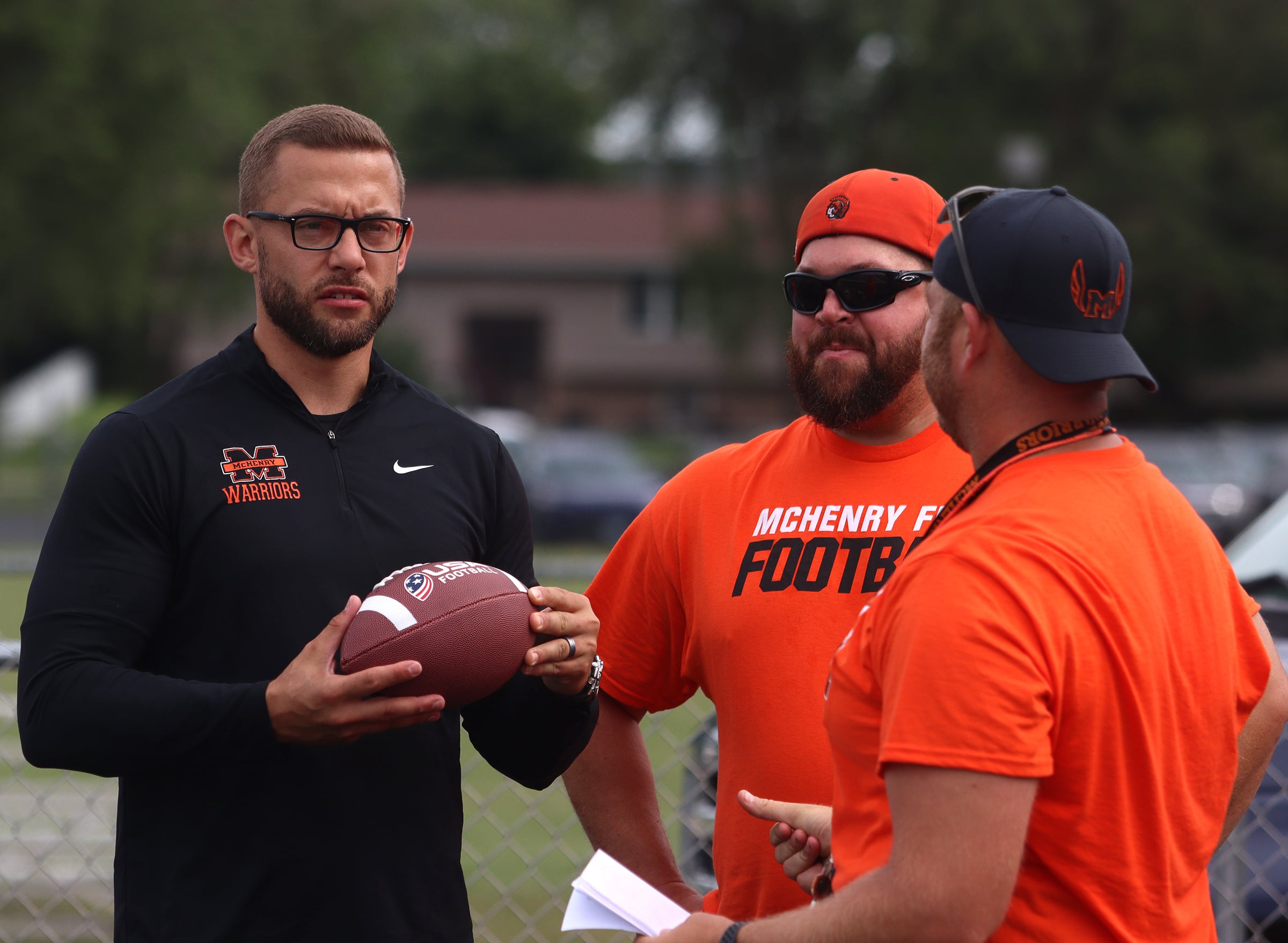 McHenry Athletic Director Chris Madson, left, speaks with his flag football coaching staff as the Chicago Bears and McHenry Community High School hosted a flag football clinic at McCracken Field Wednesday.