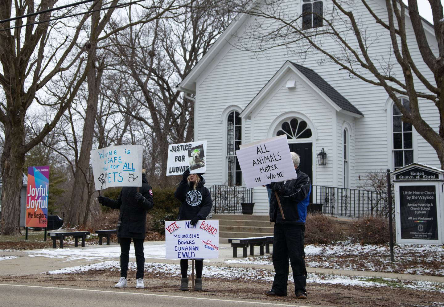 Justice for Ludwig protesters hold up signs asking for new village leadership outside a town hall meeting at the Little Home Church by the Wayside in Wayne on Saturday, Jan. 7, 2023.
