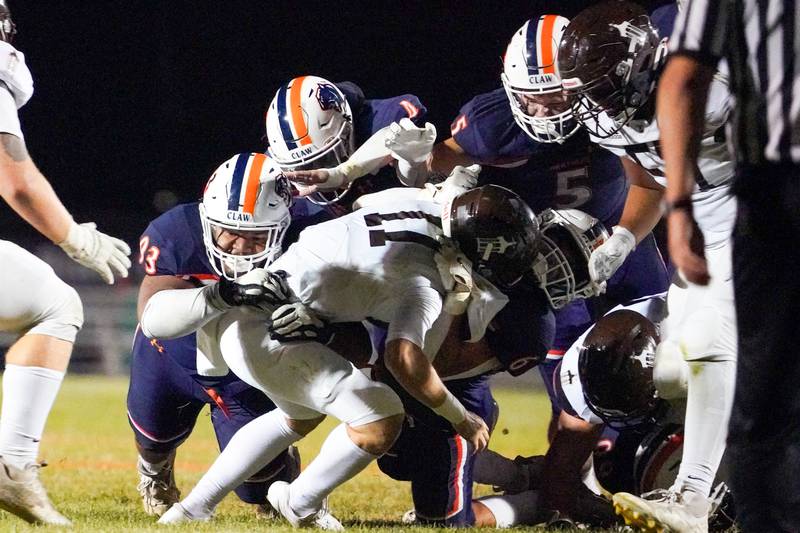 A number of Oswego defenders tackle Joliet Catholic's Lucas Simulick (11) in the backfield for a loss during a football game at Oswego High School on Friday, Sep 6, 2024.