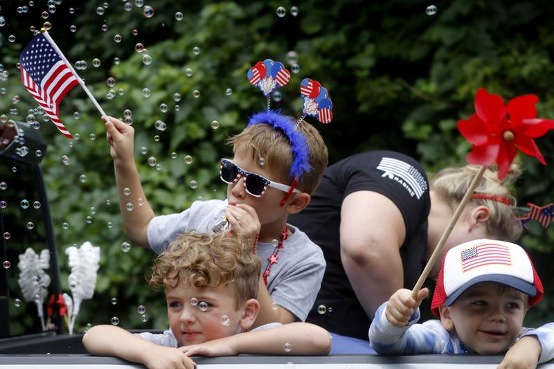 Children play in the bubbles and wave a flag from the back of a Rabine Mechanical truck Sunday, July 2, 2023 during Crystal Lake’s annual Independence Day Parade on Dole Avenue in Crystal Lake. This year’s parade feature close to 100 units.