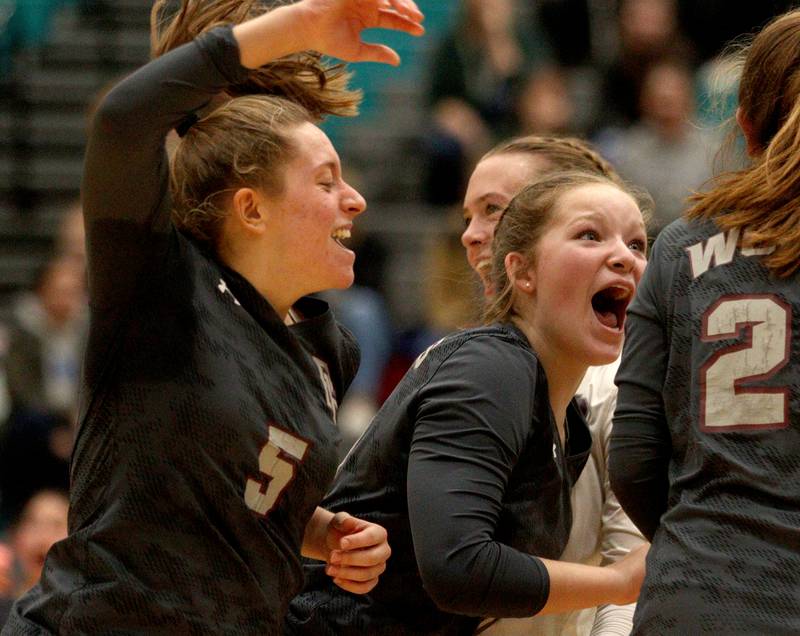 Prairie Ridge’s Grace Jansen, left, and Tegan Vrbancic, center, celebrate a point in IHSA Class 3A sectional semifinal volleyball action at Woodstock North Monday.