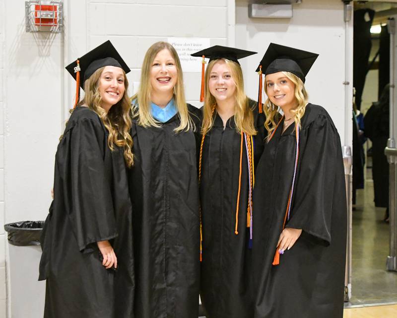 DeKalb High School graduates (from left) Lily Roach, Myalee Feeney and Isabella Holiday all pose for a photo with assistant Principal Sara Jennings (second from left) before taking part in the 2024 DeKalb High School commencement ceremony on Saturday, May 25, 2024, at the Northern Illinois University Convocation Center in DeKalb.