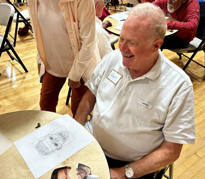 Kent Lawrence of Oregon laughs as he shares his suspect sketch during a forensic art workshop by Bethe Hughes at the Coliseum Museum of Art, Antiques, and Americana in Oregon on Saturday, Aug. 17, 2024. Hughes, a special agent and forensic artist, worked  for the Illinois State Police and was the presenter for the program.