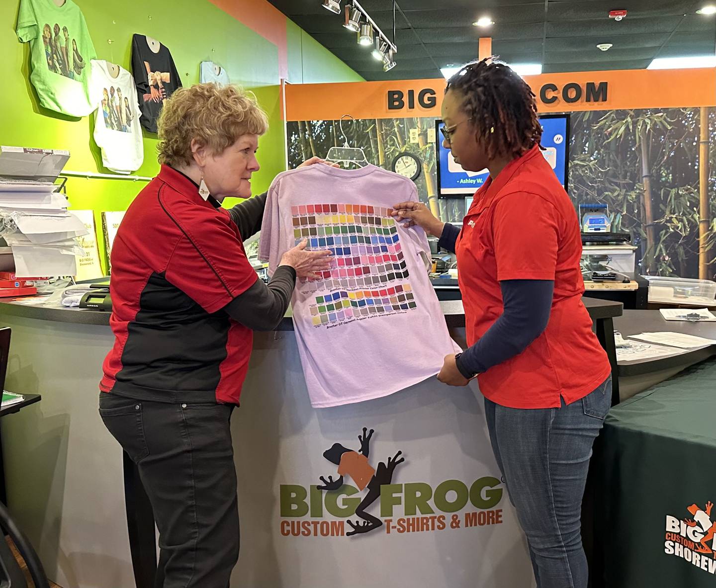 Gail Girard (left) owner of  Big Frog Custom T-Shirts & More in Shorewood. discusses a T-shirt with Tiffany Allen-Smith, co-owner of PostNet, a Big Frog neighboring shop. Girard is celebrating her 10th anniversary as a Big Frog franchise owner in the same Shorewood location.