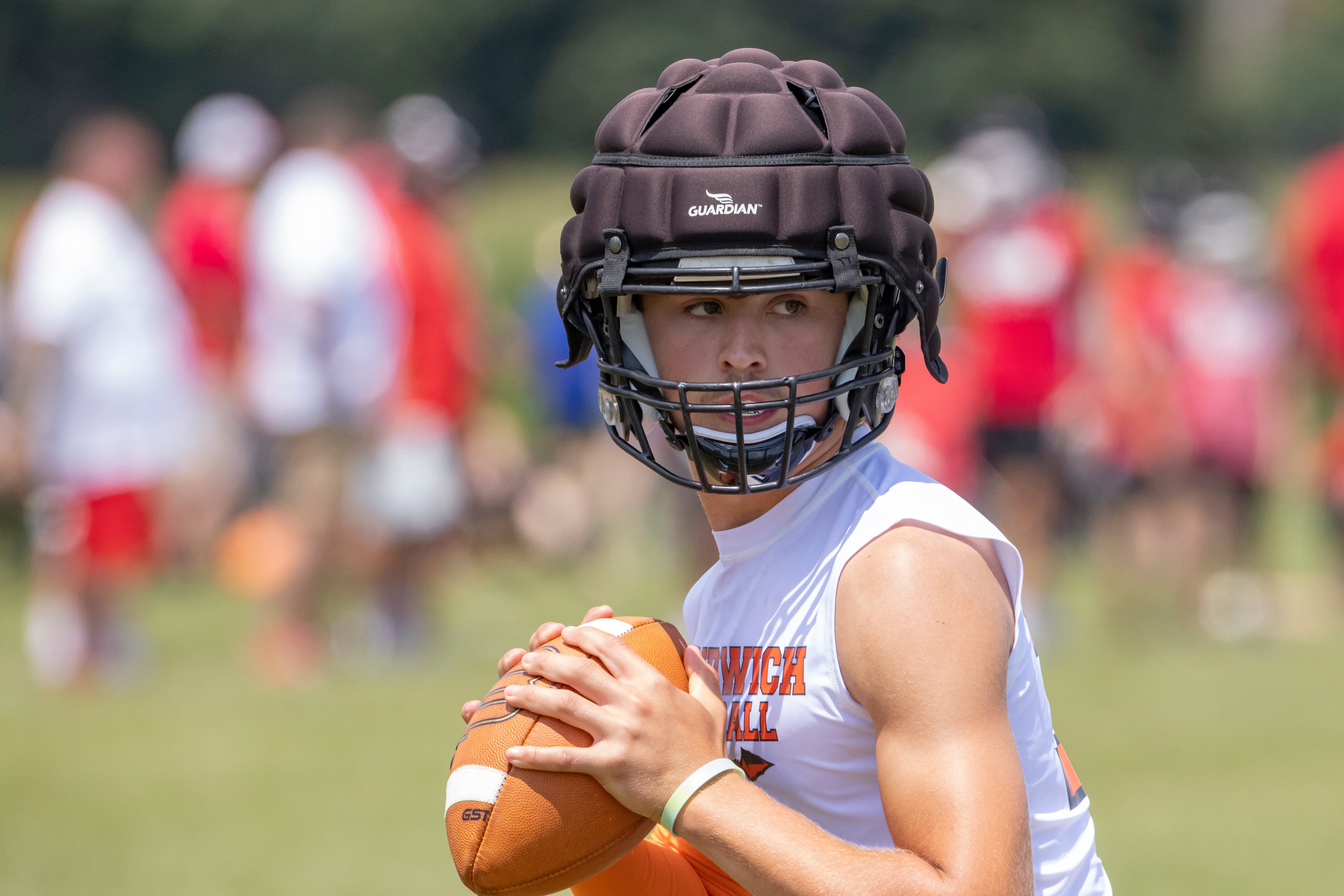 Sandwich quarterback Brady Behringer looks for a receiver downfield during a multiple high school practice football meet at Princeton High School on July 20, 2024.