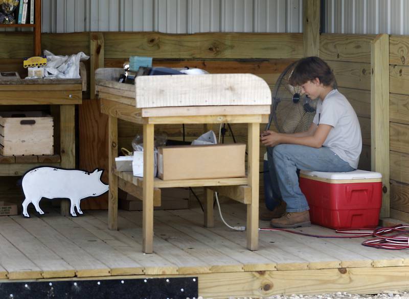 John Patyk, 13, tries to keep cool in front of a fan as he tends to his family's Patyk's Farm Market and Greenhouse near Richmond on July 25, 2023. With temperatures in the nineties and high humidity forecasted, cooling centers will be open throughout McHenry County.