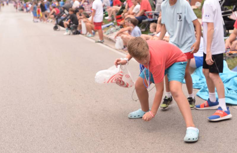 Luke Haggerty of Downers Grove picks up some of the candy during the Downers Grove Fourth of July Parade on Thursday, July 4, 2024.