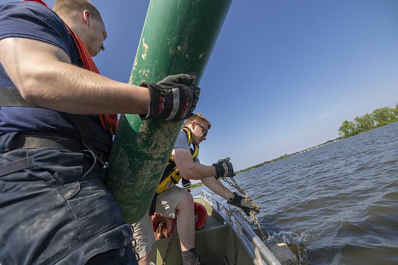 Firefighter Brayden Porter (right) sinks a heavy concrete weight for the buoy held by Dylan Scudder Wednesday, May 15, 2024. Sterling and Rock Falls departments both spent the morning placing buoys out into the channel.