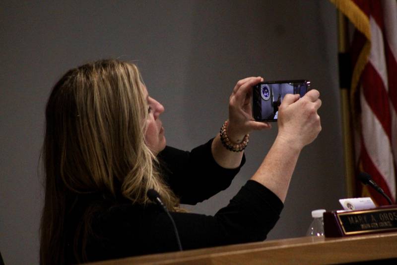 Dixon City Council member Mary Oros lines up a shot with a cell phone camera as she photographs outgoing Mayor Li Arellano as he gavels the session to order on Monday, May 1, 2023.