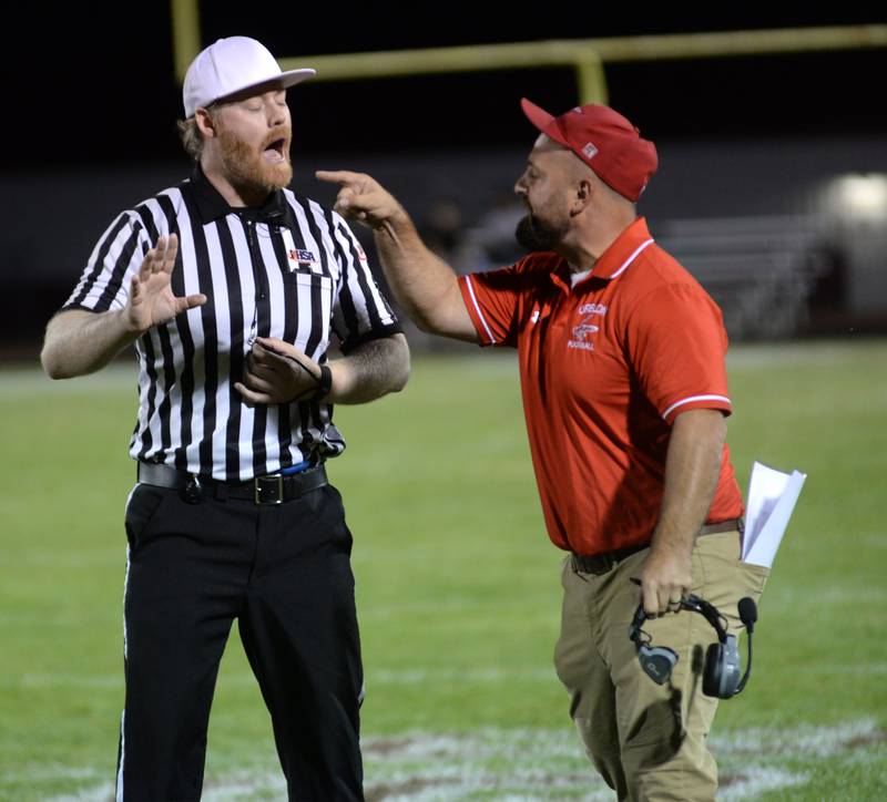 Oregon coach Broc Kundert discusses a call with one of the umpires during action against Genoa-Kingston on Friday, Sept. 13, 2024 at Landers-Loomis Field in Oregon.