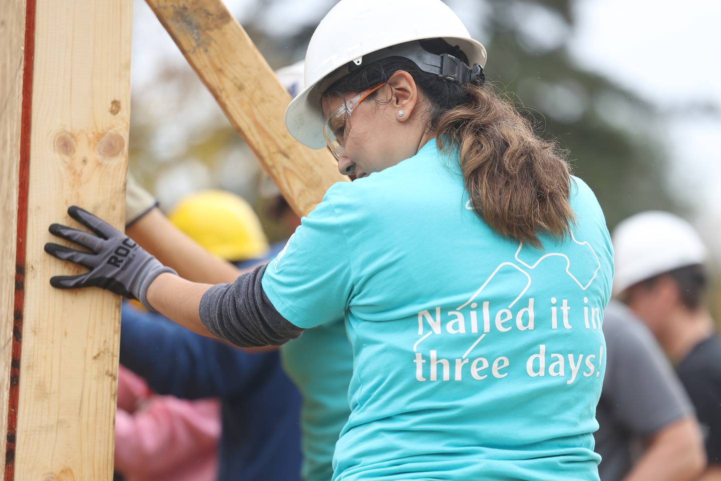 Volunteer Maricsa Sanchez, CITCO Health Service Manager, holds a section of a wall frame as it is put in place of a home being built by Habitat for Humanity on Wednesday, Oct. 25, 2023 in Lockport.