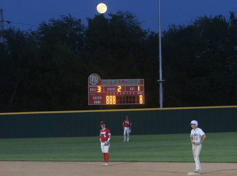 A nearly full moon shines above Huby Sarver Field as Ottawa players Jacob Rosetto and teammate Jack Henson along with Plano's Jake Decker play baseball during the Class 3A Regional semifinal game on Wednesday, May 22, 2024 at Huby Sarver Field in La Salle.