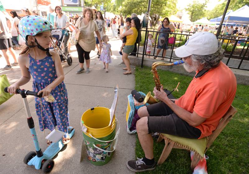 Hannah Davis of LaGrange stops to listen to the sounds of Paul Velat of Lombard during the LaGrange Farmers Market Thursday June 7, 2024.